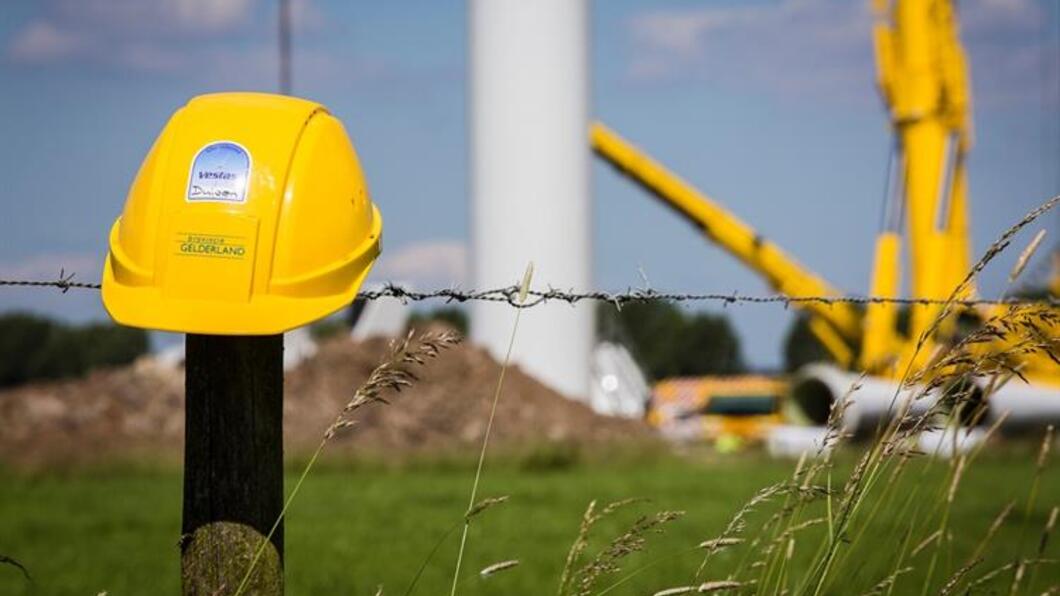 Bouw windmolen met op voorgrond veiligheidshelm