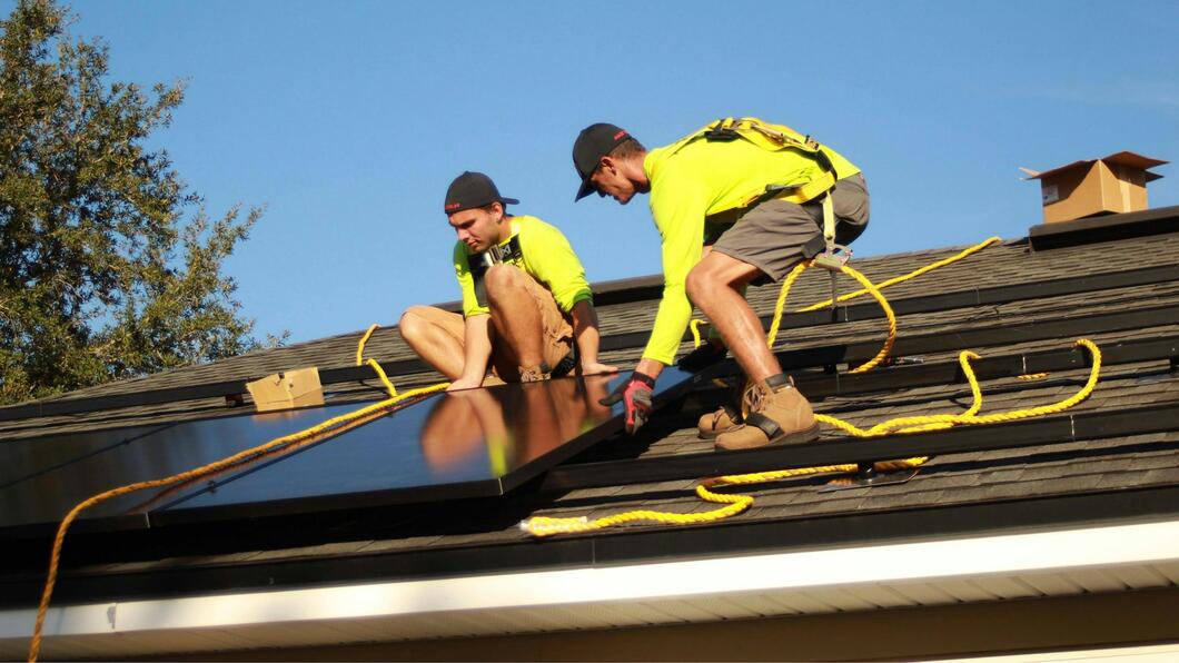 mensen die samen zonnepanelen op dak leggen