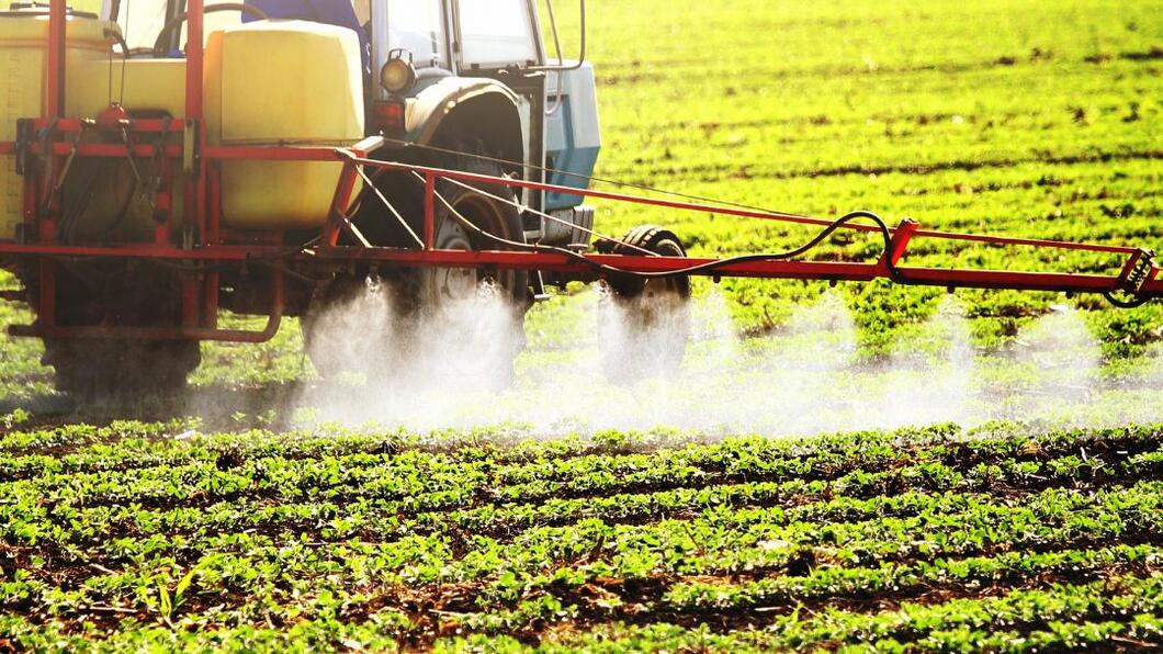 Tractor die een veld bespuit 