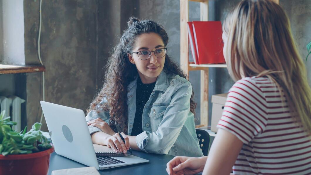 twee vrouwen achter een laptop in gesprek