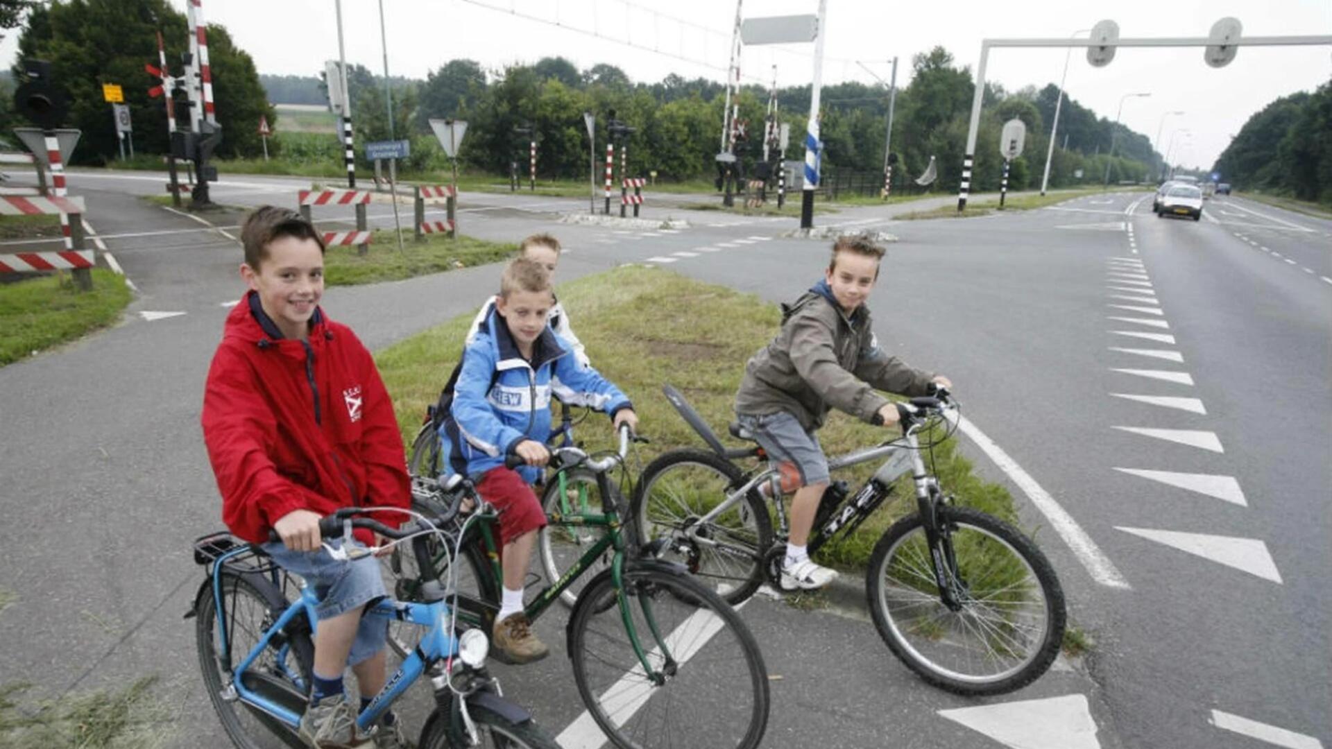 Kinderen met een fiets vlakbij een drukke weg